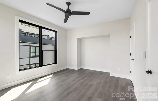 an empty room with wooden floor cabinet and windows