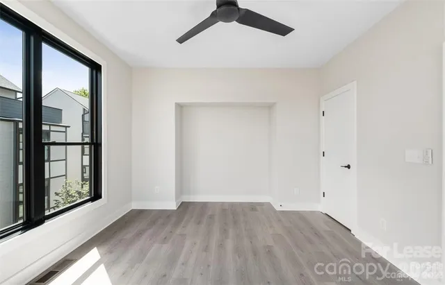 a view of empty room with wooden floor and fan