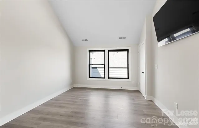 an empty room with wooden floor and windows