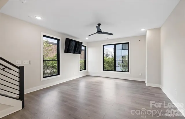 a view of an empty room with window and wooden floor