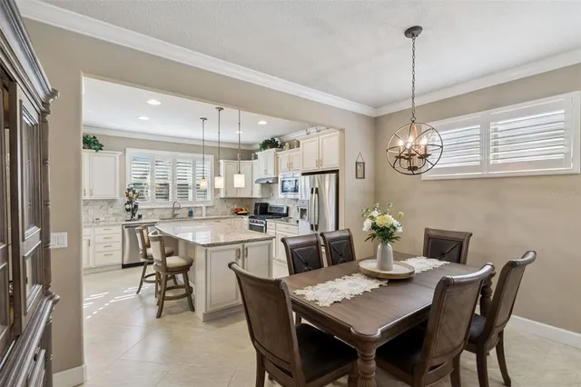 a dining room with stainless steel appliances a table chairs and a kitchen view