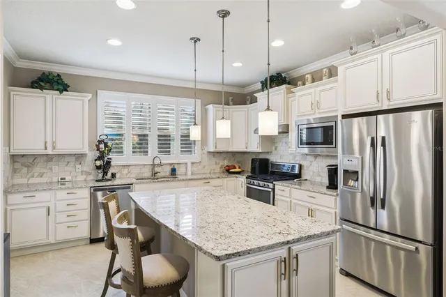 a kitchen with stainless steel appliances granite countertop a sink refrigerator and cabinets