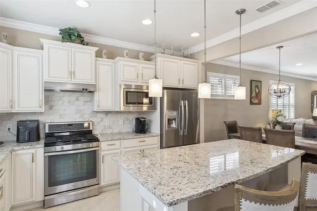 a kitchen with stainless steel appliances granite countertop a sink a stove a refrigerator and cabinets