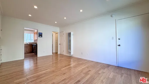 a view of an empty room with wooden floor and closet