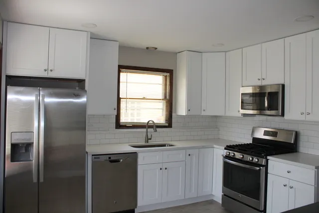 a kitchen with white cabinets and stainless steel appliances