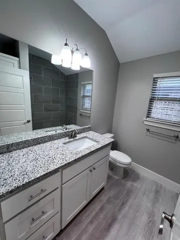 a bathroom with a granite countertop sink a toilet and mirror