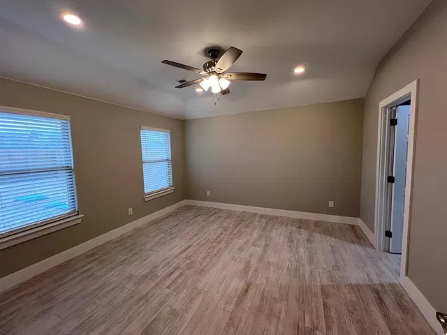 a view of empty room with wooden floor and fan