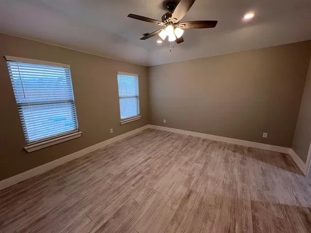 a view of empty room with wooden floor and fan