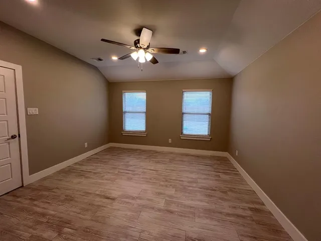 a view of an empty room with chandelier fan and fire place
