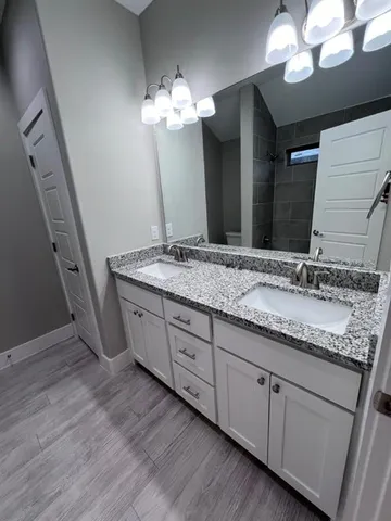 a bathroom with a granite countertop sink a light fixture and a mirror