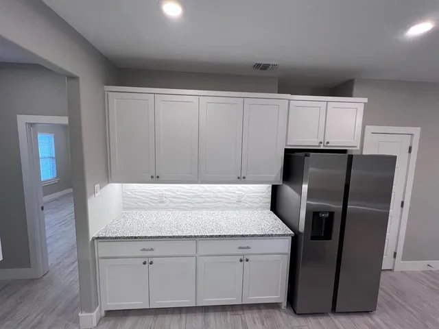 a kitchen with granite countertop a refrigerator a stove and cabinets