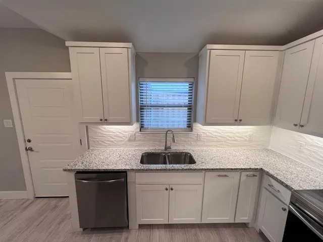 a kitchen with granite countertop a sink and a stove