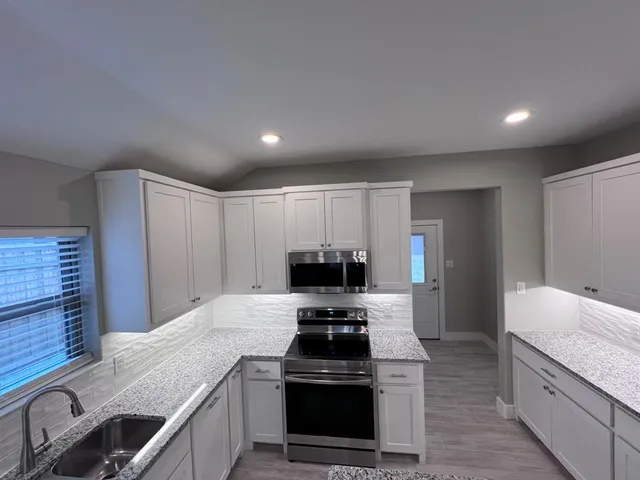 a kitchen with granite countertop a stove and a sink