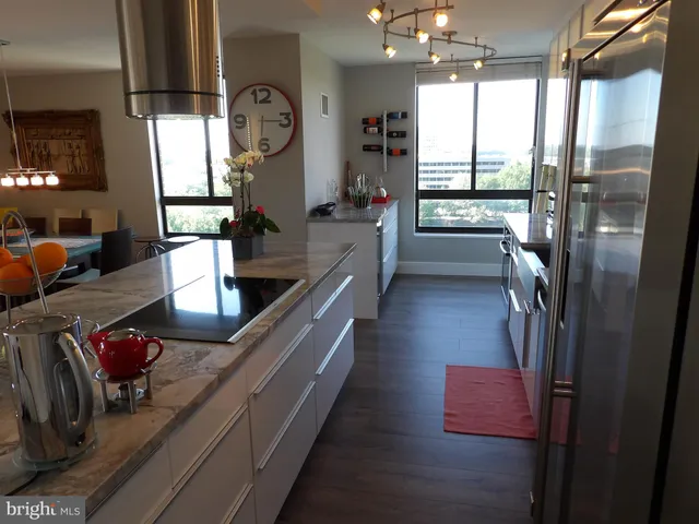 a kitchen with kitchen island granite countertop a sink appliances cabinets and a large window