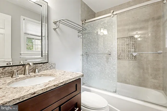 a bathroom with a granite countertop shower sink vanity and toilet