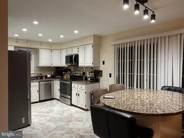 a kitchen with stainless steel appliances granite countertop a refrigerator a stove a sink dishwasher and a microwave with wooden floor