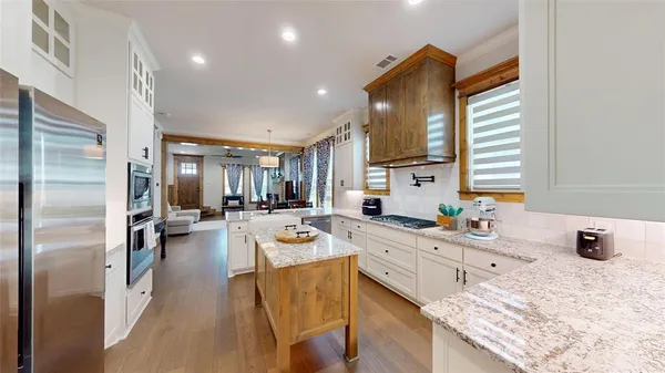 a kitchen with stainless steel appliances kitchen island granite countertop a refrigerator and a sink