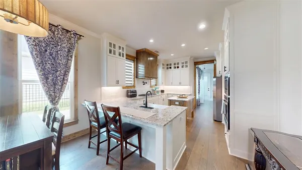 a kitchen with stainless steel appliances kitchen island granite countertop a dining table chairs and a refrigerator