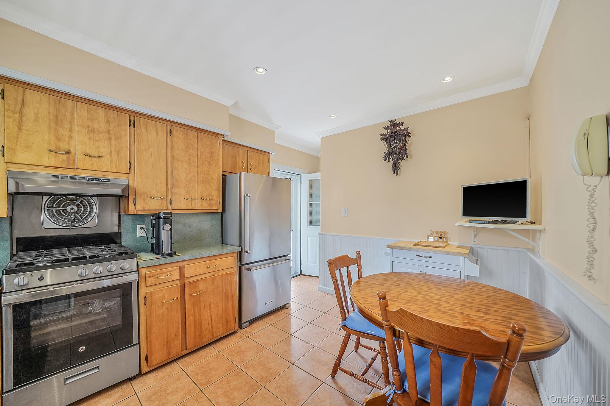 256-12 87th Road Floral Park, NY 11001 - Photo 11 of 33 a kitchen with stainless steel appliances a stove a refrigerator a microwave a dining table and chairs