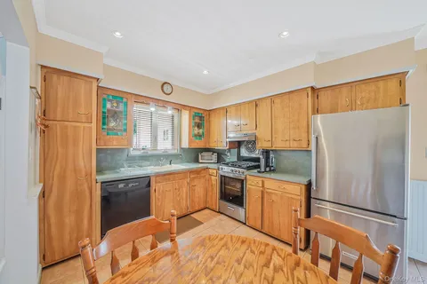 a kitchen with stainless steel appliances granite countertop a refrigerator a sink dishwasher a stove with white cabinets and wooden floor