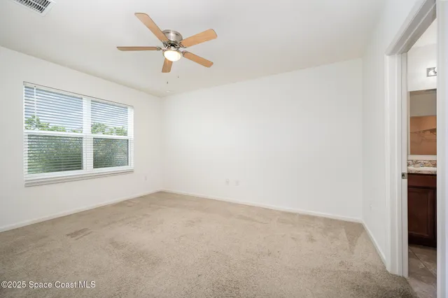 an empty room with a window and a ceiling fan