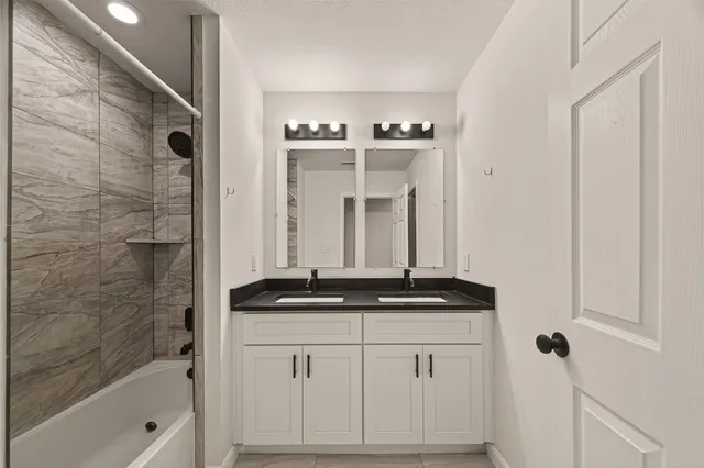 a bathroom with a granite countertop sink a mirror and a bathtub