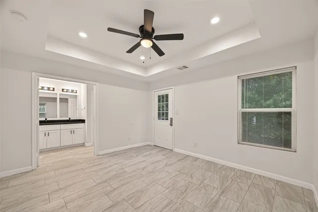 a view of a livingroom with a ceiling fan & windows