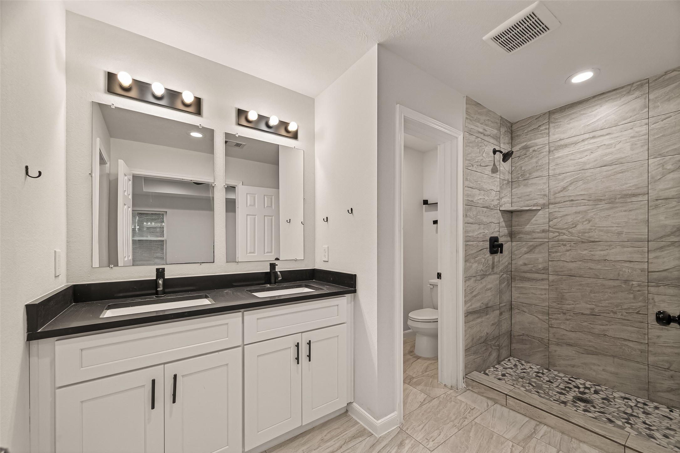 4302 Hirsch Road, Unit B Houston, TX 77026 - Photo 25 of 30 a bathroom with a double vanity sink a mirror and a shower