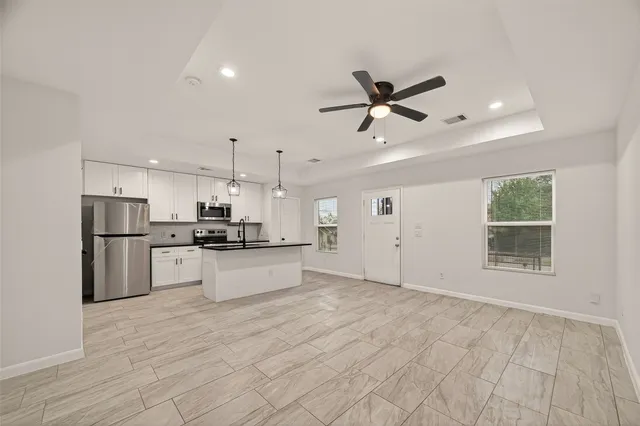 a large kitchen with kitchen island a stove a sink dishwasher and a refrigerator with wooden floor