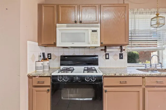 a kitchen with granite countertop stainless steel appliances a stove sink and cabinets