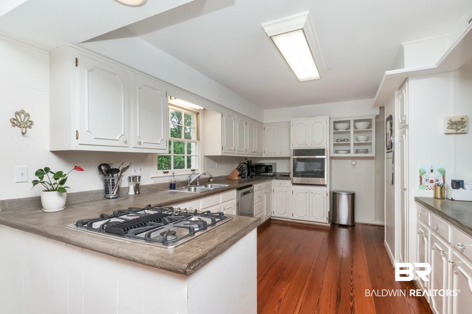 117 Ridgelawn Drive West Mobile, AL 36608 - Photo 13 of 31 Kitchen featuring a sink, stainless steel appliances, a peninsula, white cabinetry, and dark wood-style floors