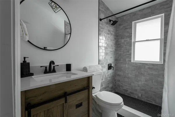 a bathroom with a granite countertop toilet sink and mirror
