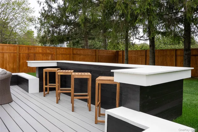 a view of a patio with table and chairs with wooden floor and fence