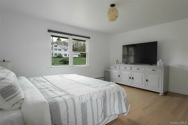 a bedroom with a bed and a flat tv screen on dresser