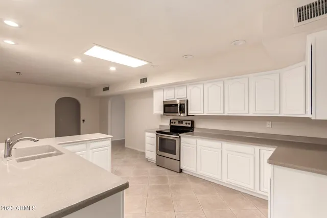 a kitchen with stainless steel appliances a sink stove and white cabinets