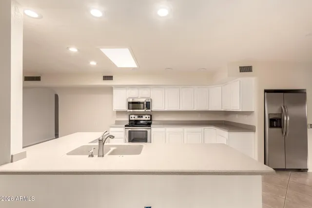 a kitchen with stainless steel appliances kitchen island granite countertop a refrigerator and a sink