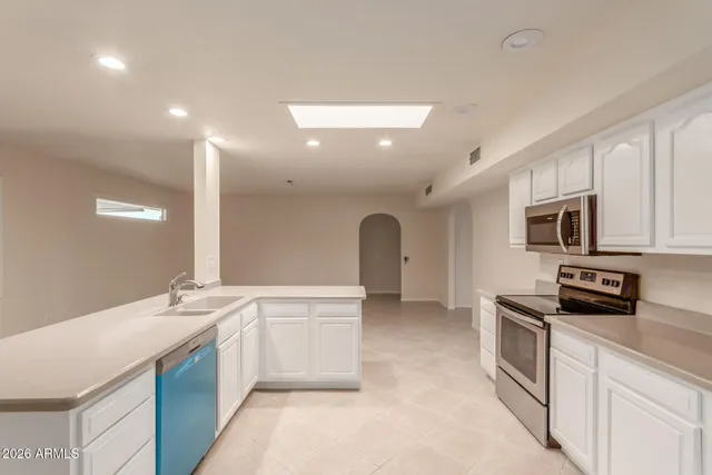 a large kitchen with stainless steel appliances a stove a sink a microwave and refrigerator