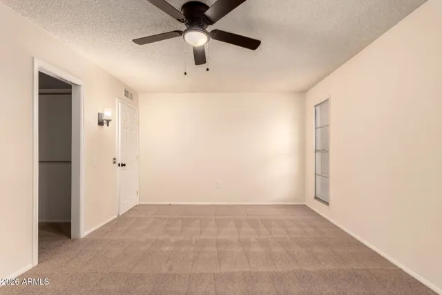 an empty room with ceiling fan and window