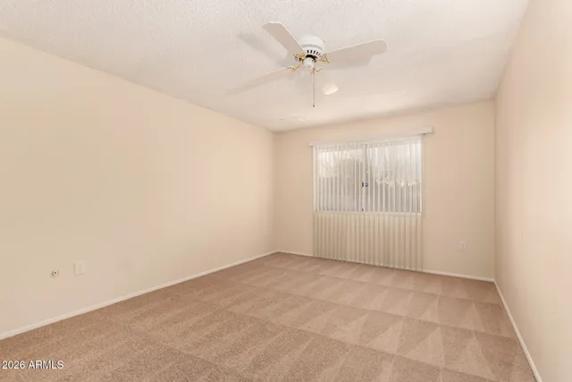 an empty room with a ceiling fan and windows