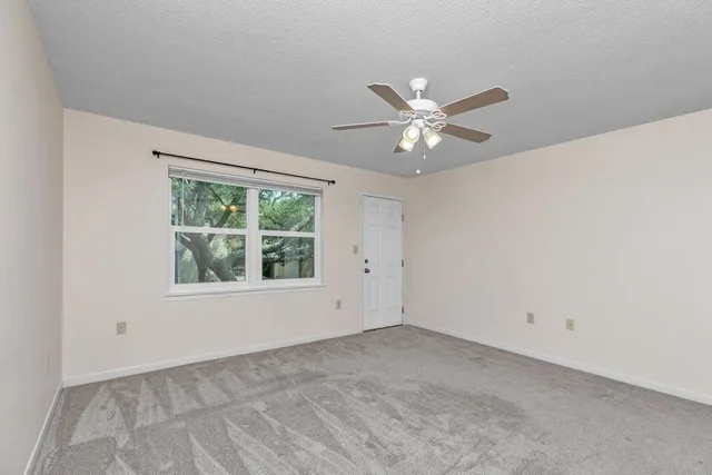 an empty room with a window and a fan