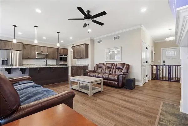 a living room with couches and kitchen view with wooden floor