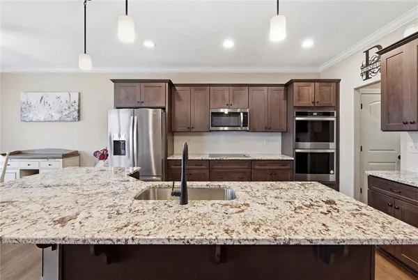 a view of kitchen island a sink wooden floor wooden floor and a refrigerator