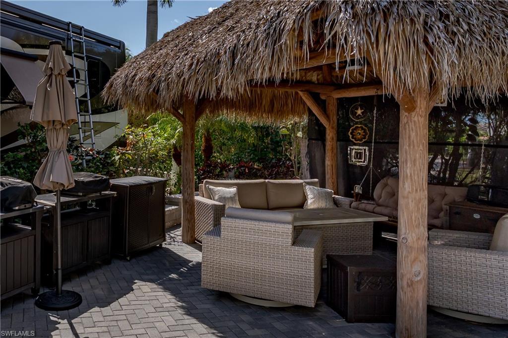 13580 Snook Circle Naples, FL 34114 - Photo 6 of 33 a view of a patio with table and chairs under an umbrella with a barbeque grill and plants