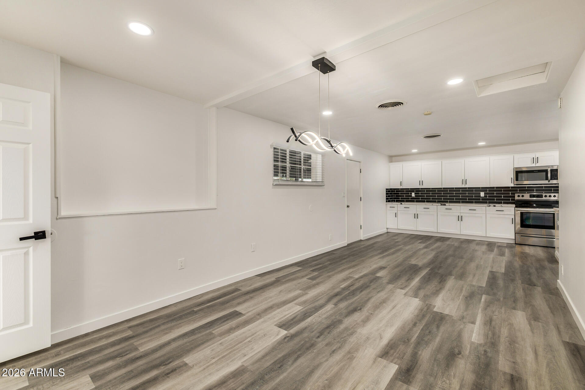 533 West 18th Street Tempe, AZ 85281 - Photo 12 of 52 an empty room with wooden floor kitchen view and windows