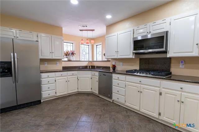 a kitchen with white cabinets stainless steel appliances and a sink