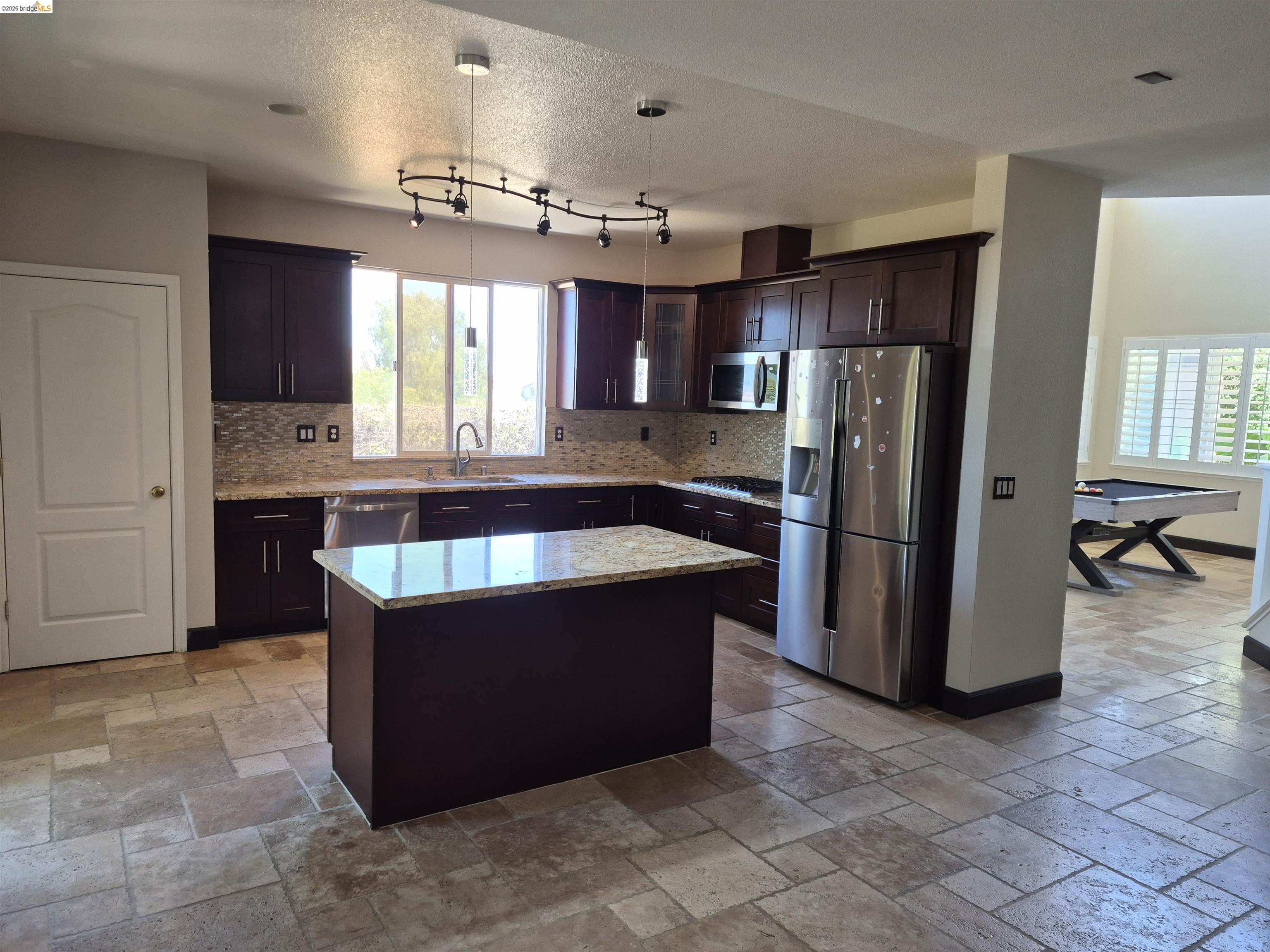 149 Oakpoint Court Bay Point, CA 94565 - Photo 2 of 22 Spacious kitchen featuring dark wood cabinetry, stainless steel appliances, a center island with a granite countertop, and tiled flooring