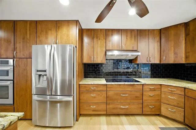 a kitchen with stainless steel appliances granite countertop a refrigerator and a stove