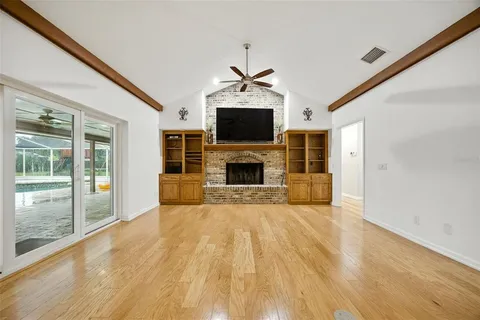 a view of a livingroom with a fireplace wooden shelves and windows
