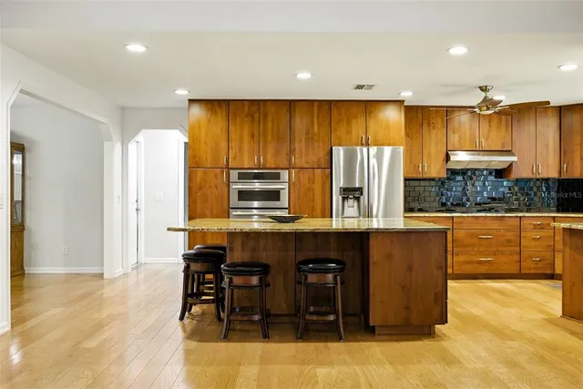 a kitchen with stainless steel appliances a dining table chairs and a refrigerator