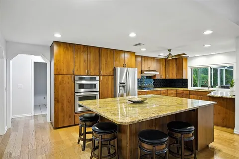 a kitchen with stainless steel appliances granite countertop a table chairs sink refrigerator and stove